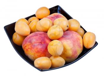 fresh peaches and apricots in black plate isolated on white background