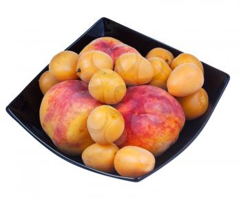 peaches and apricots in black plate isolated on white background