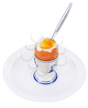eating of soft boiled egg in egg cup on white plate isolated on white