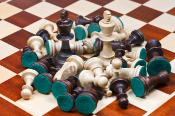 white and black kings in middle of scattered chess pieces on chessboard