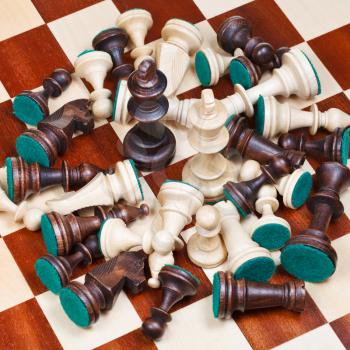 white and black kings in middle of spillage of chess pieces on chess board