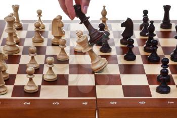 hand with black king drops white king on chessboard in chess game