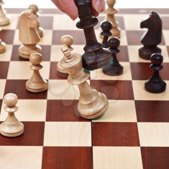 hand with black king wins white king on chessboard in chess game