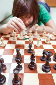 little girl girl moves knight playing chess lying on couch