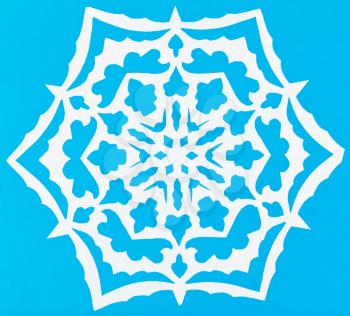 hand made cut out white snowflake on blue paper