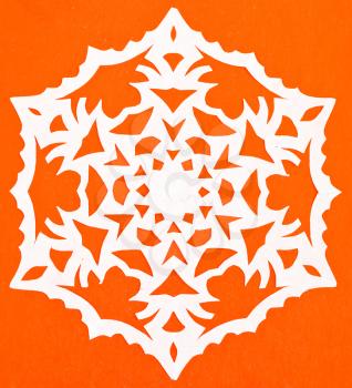 hand made cut out white snowflake on orange paper