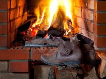 boots are dried near fire in fireplace in evening time