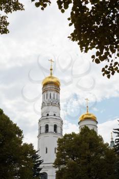 view of Ivan the Great Bell Tower through green tree in Moscow Kremlin
