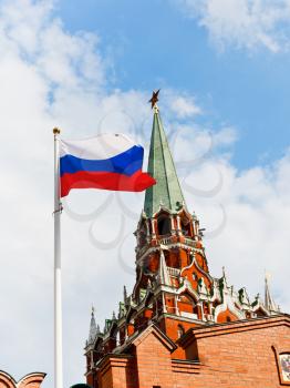 Russian state flag fluttering in wind with Kremlin Troitskaya tower on background