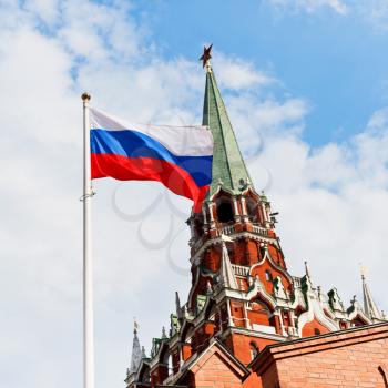 Russian state flag flying in wind with Kremlin Troitskaya tower on background