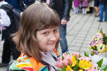 Schoolgirl with bouquet of flowers goes to primary school in autumn