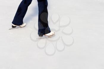 legs with skates on ice of outdoor open skating rink