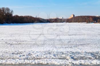 melting ice on frozen urban lake in early spring day