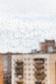 raindrops on glass window with town house background