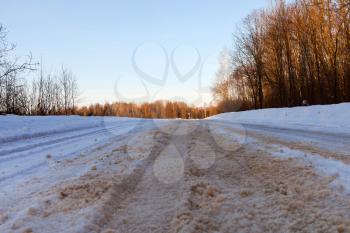 empty snowy country road in winter afternoon