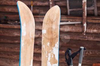 pair of wide wooden hunting skis and log house wall in winter day