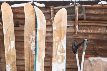 two pairs of wide skis and log house wall in winter day