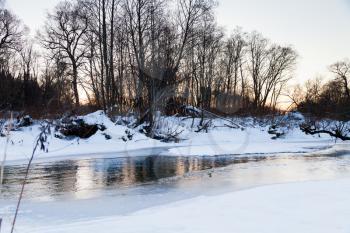 snow banks of forest river at winter sunset