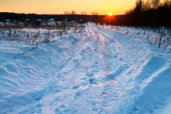 sunset under blue winter snowbound country road