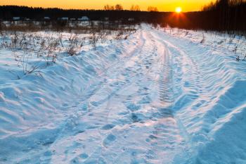sunset under blue winter snowcovered country road