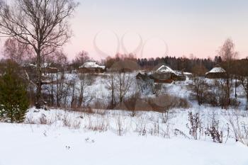 pink winter sunset under snowy wooden houses in country
