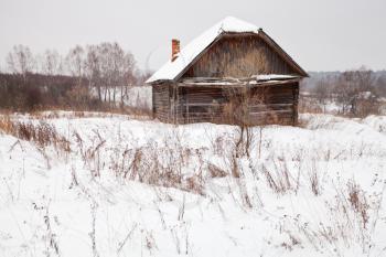 abandoned wooden house in snow-covered village in winter day