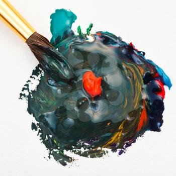 paintbrush merges multicolored watercolors paints and red gouache drop close up