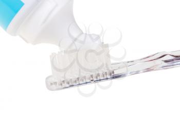 squeezing toothpaste from tube on toothbrush close up isolated on white background