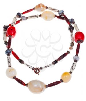 necklace from natural mineral beads of large agate stones, red coral, carved horn and bone isolated on white background