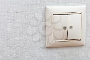 two button wall-mounted light switch on room wall close up