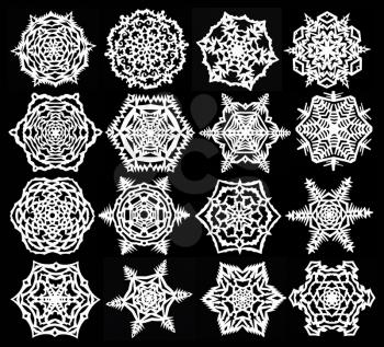 set of hand made cut out white snowflakes on black paper background