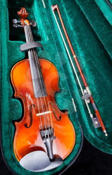 modern small violin with bow in green velvet case close up