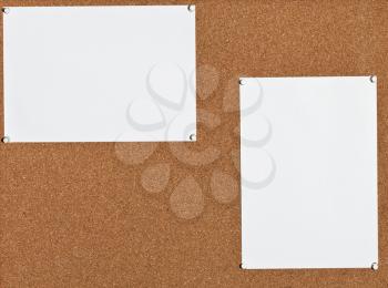 two blank white sheets of paper on cork board