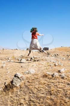 girl jumping on Zorats Karer (Carahunge) plateau - pre-history megalithic monument in Armenia