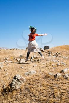 young woman jumping on Zorats Karer (Carahunge) plateau - pre-history megalithic monument in Armenia