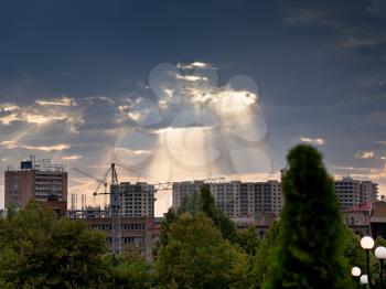 rays of evening sun through clouds illuminate new buildings in Yerevan, Armenia