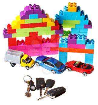 door key, vehicle keys, three model cars and plastic block house isolated on white background