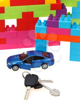 door key, vehicle keys close up, blue model car and plastic block house on white background