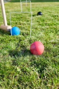 hitting of blue ball in game of croquet on green lawn in summer day