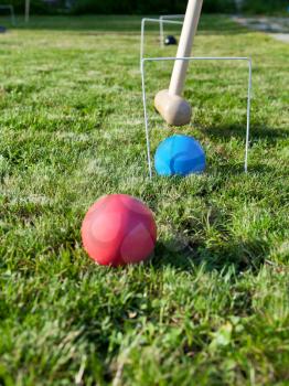 hoop and balls in game of croquet on green lawn in summer day
