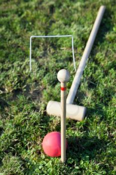 mallet, red ball in game of croquet on green lawn in summer day