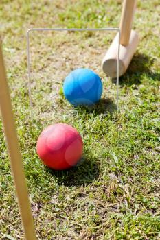 hitting blue ball through hoop in game of croquet on green lawn