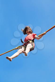 girl jumps on bungee cord with blue sky background