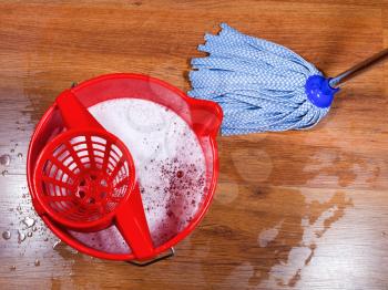 red bucket and mopping of wooden floors
