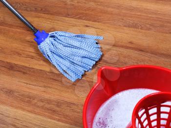 red bucket with washing water and mopping of wooden floors