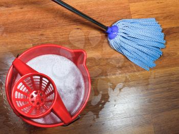 mopping of wooden floors and red bucket with washing water