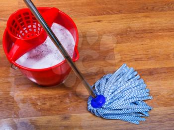 blue mop and red bucket on wet floor