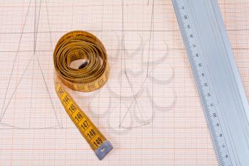 yellow measure tape and metal ruler at graph paper