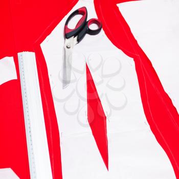 fitter scissors and cutting out woolen fabric along pattern lines for tailoring red dress
