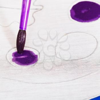 painting violet pattern on silk canvas with brush close up